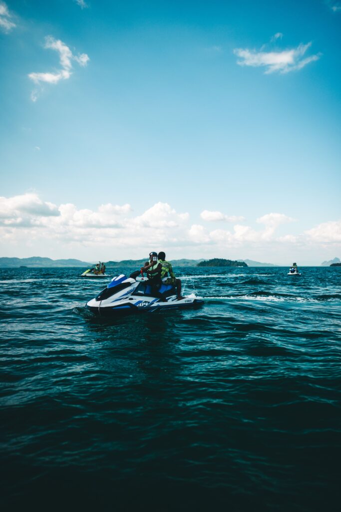 Tourists riding a jet ski on open blue waters during a water sports adventure tour in Phuket Thailand.