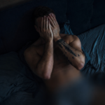 Tourist sitting on a bed after a Bangkok nightlife scam experience in Thailand