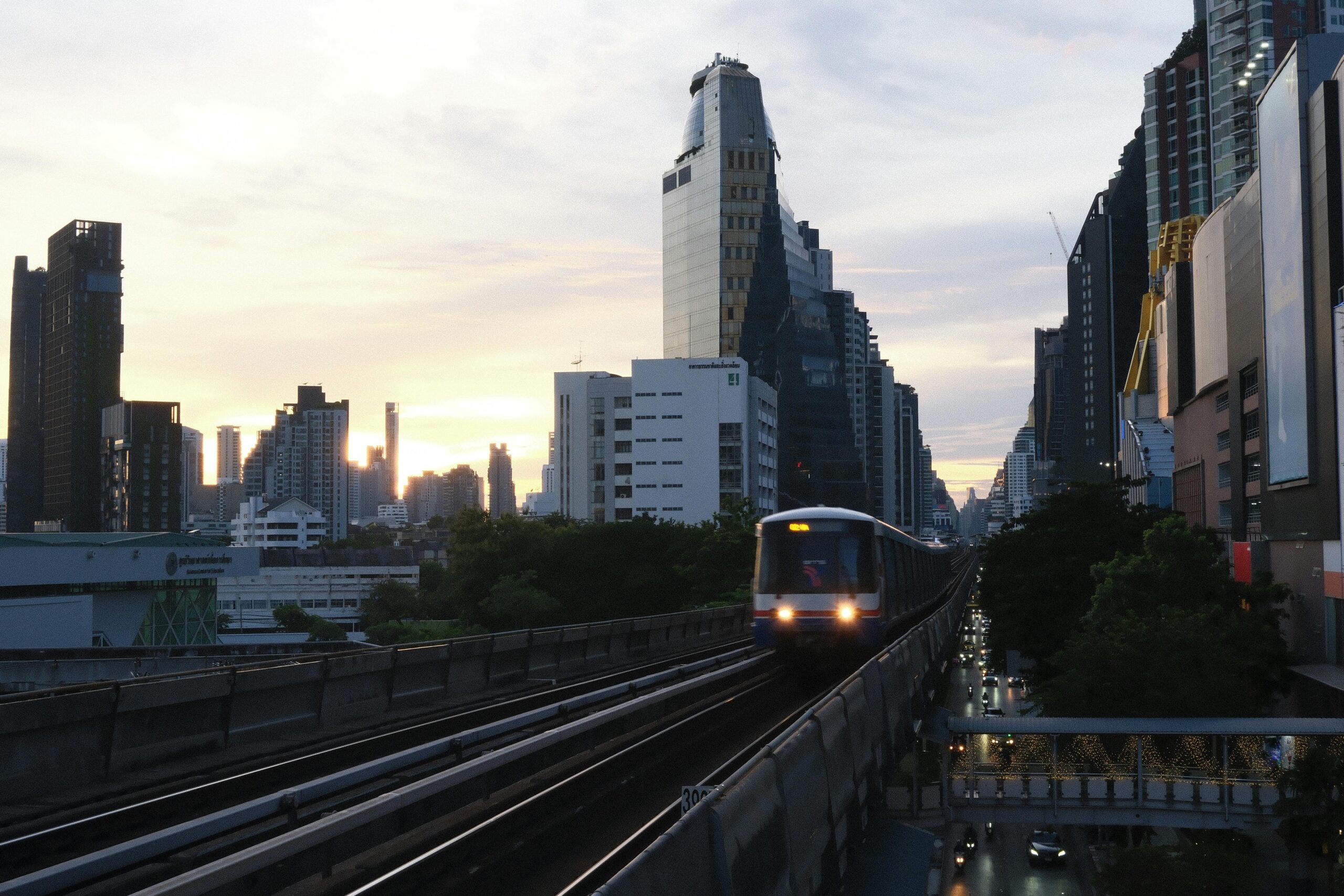 BTS Skytrain on elevated tracks with Bangkok skyline at dusk, featured in transport guide