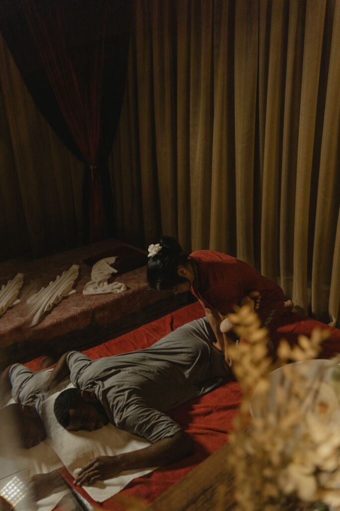 Therapist providing an authentic traditional Thai body massage treatment to a relaxed client in a tranquil spa environment in Thailand.