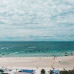 Aerial view of the expansive white sand and turquoise water at Pattaya Beach in Chon Buri, Thailand, filled with speedboats and swimmers, highlighting a top self-drive coastal day trip from Bangkok.