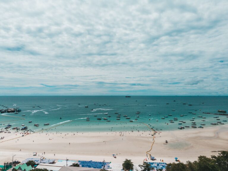 Aerial view of the expansive white sand and turquoise water at Pattaya Beach in Chon Buri, Thailand, filled with speedboats and swimmers, highlighting a top self-drive coastal day trip from Bangkok.