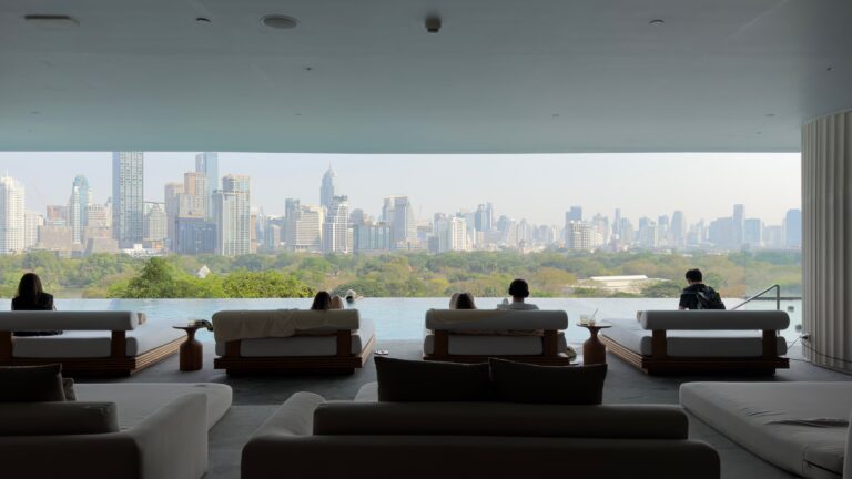 Relaxing luxury wellness lounge and infinity pool overlooking the Bangkok city skyline and lush park, representing wellness tourism in Thailand.